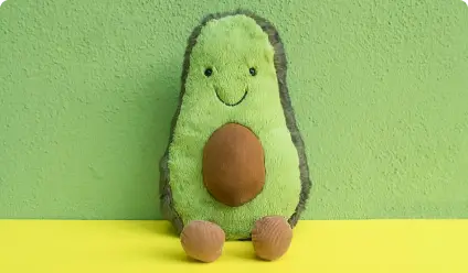 Smiling avocado plush toy on a green background.